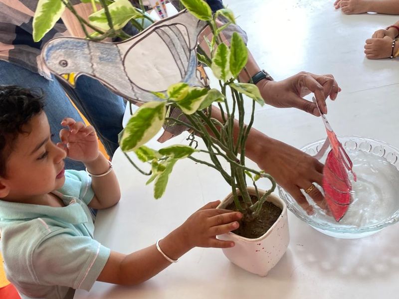 A child planting a sapling in a glass jar during a nature activity