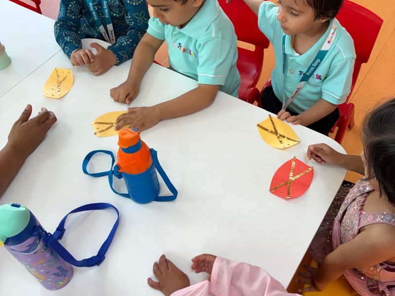 Children cutting and sticking coloured paper during an art and craft session