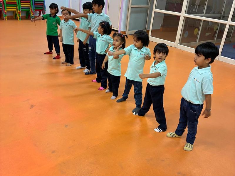 Children spread out across the open indoor hall used for dance and movement sessions
