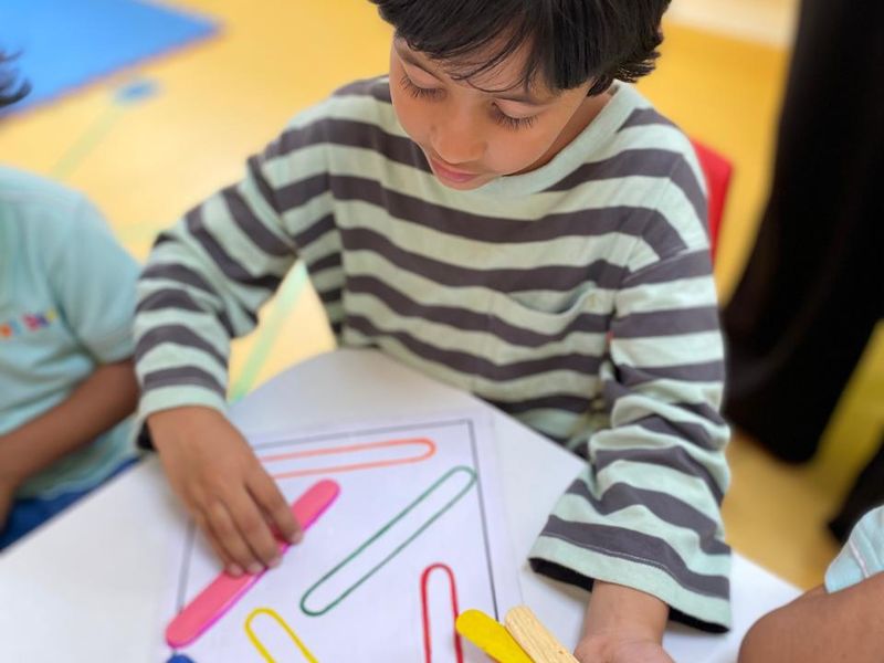 A child matching coloured craft sticks to a pattern card in the Montessori Lab