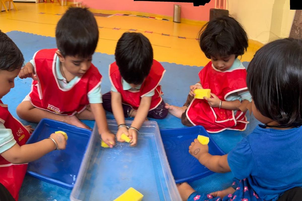 School-age children playing together at a blue water and sponge table