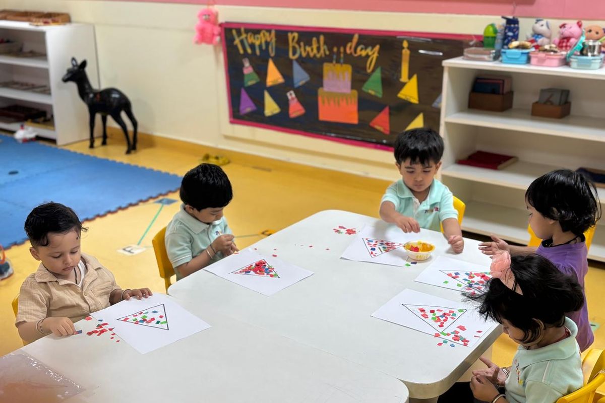 A bright classroom with low tables, open shelves and children working on an activity