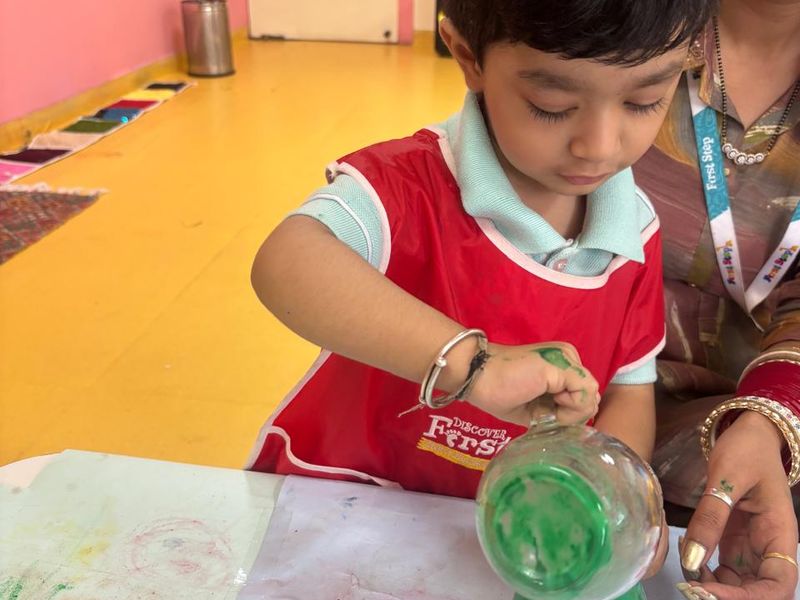 A Pre-Nursery child pouring coloured water during a messy-play activity