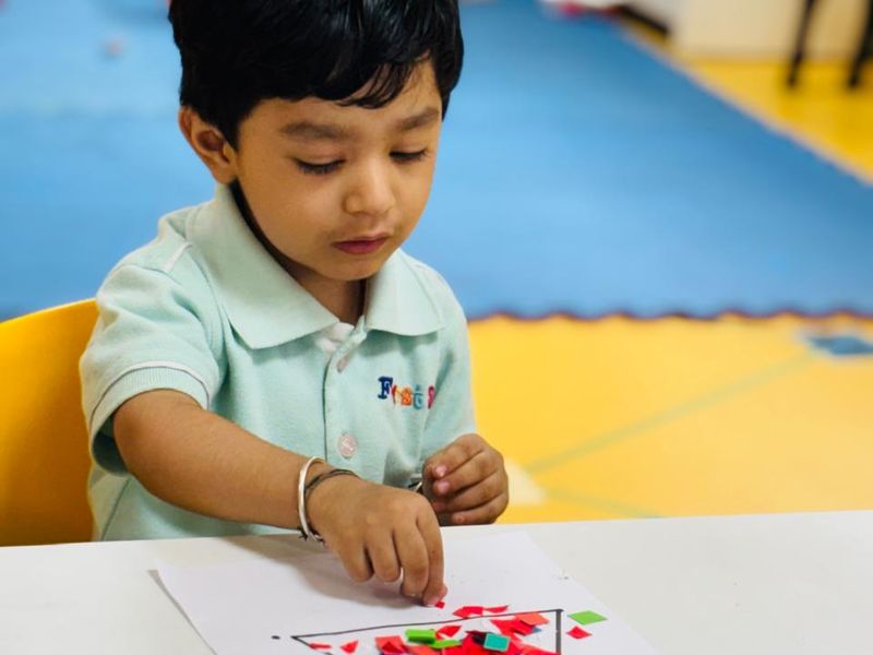 A child filling a shape with coloured paper dots during a fine-motor activity